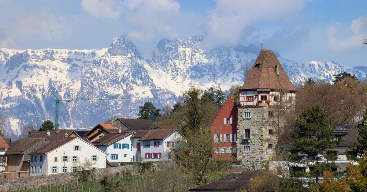 Scenic view of Vaduz with traditional houses and snow-capped mountains in the background.