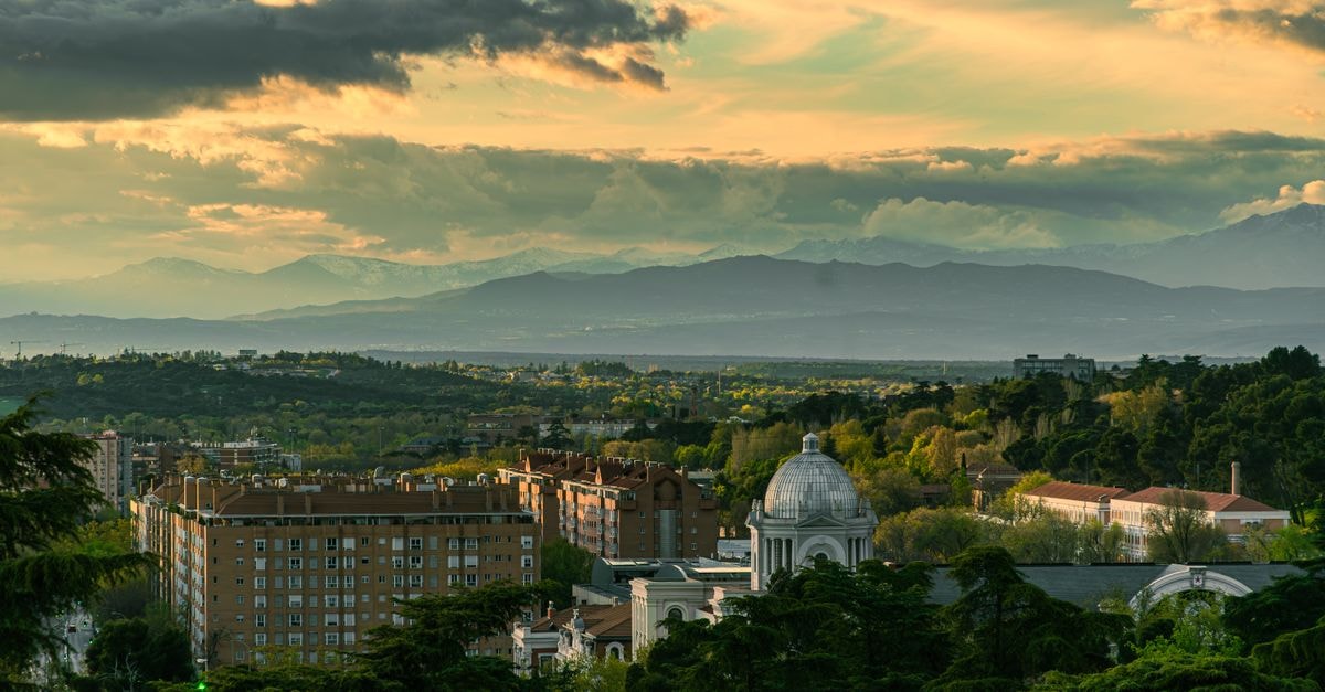 Hostal Victoria I in Madrid: A Family-Run Guesthouse on Calle de Carretas Since 1987 Panoramic view of Madrid's urban landscape with mountains and a dramatic sky at dusk.