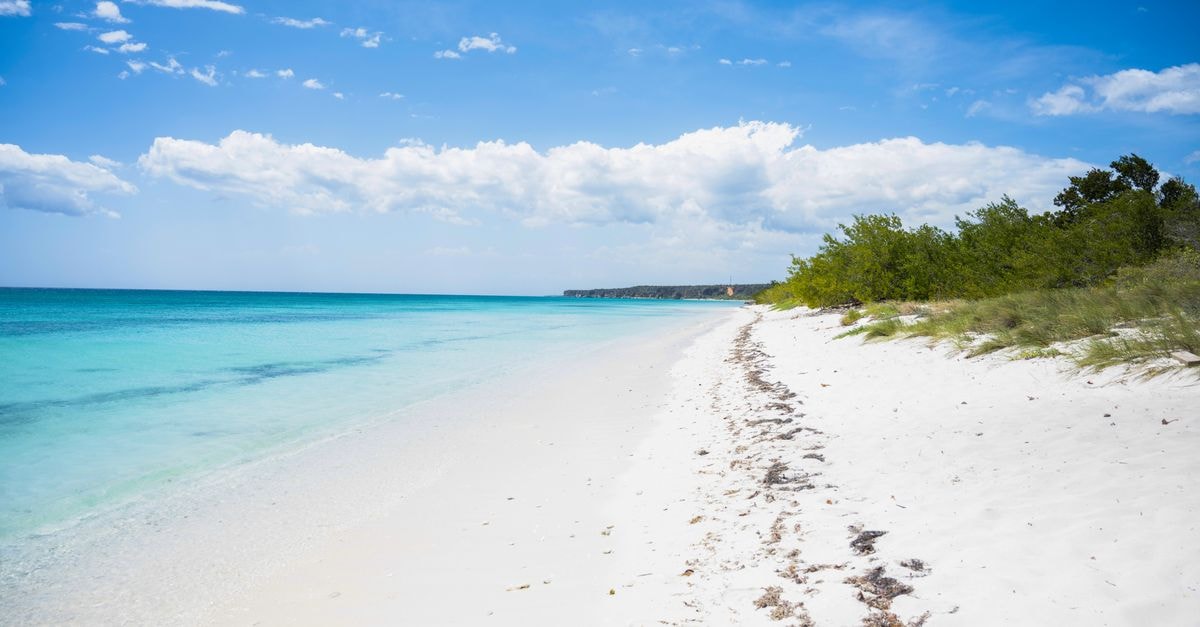 A serene beach with turquoise water and white sand in Pedernales, Dominican Republic, under clear blue skies.