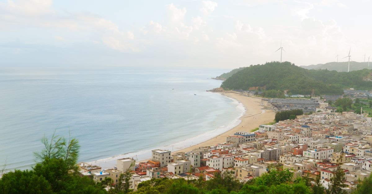 Chizhou Travel Guide: Planning Tips, Costs and Things to Do A picturesque view of a coastal city with sandy beaches and distant wind turbines.