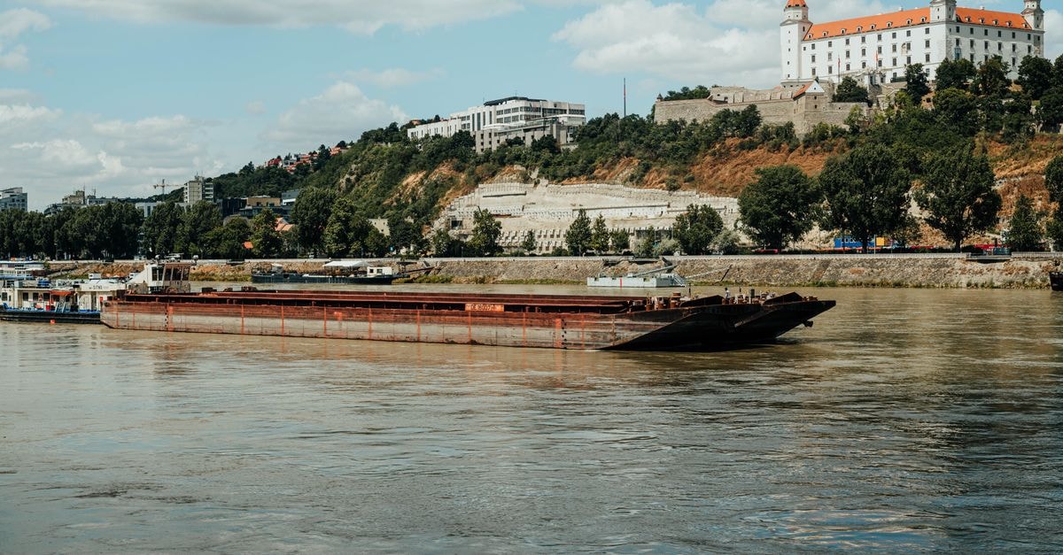 Slow Days on the Danube: A Giurgiu Travel Guide A picturesque barge cruising the Danube river with Bratislava Castle in the background.