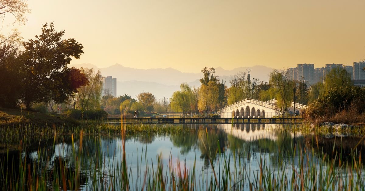 The Ritz-Carlton, Chengdu in Sichuan: Sky-High Rooms Overlooking Tianfu Square Serene river scene with a white bridge in Chengdu, Sichuan, China during a golden sunset.