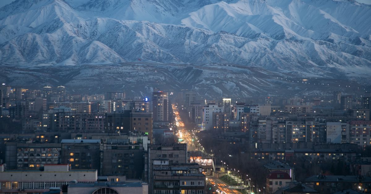 Bishkek Travel Guide: A Laid-Back Capital Beneath the Tian Shan A breathtaking view of Bishkek with snow-capped mountains at twilight, showcasing its urban skyline and natural beauty.