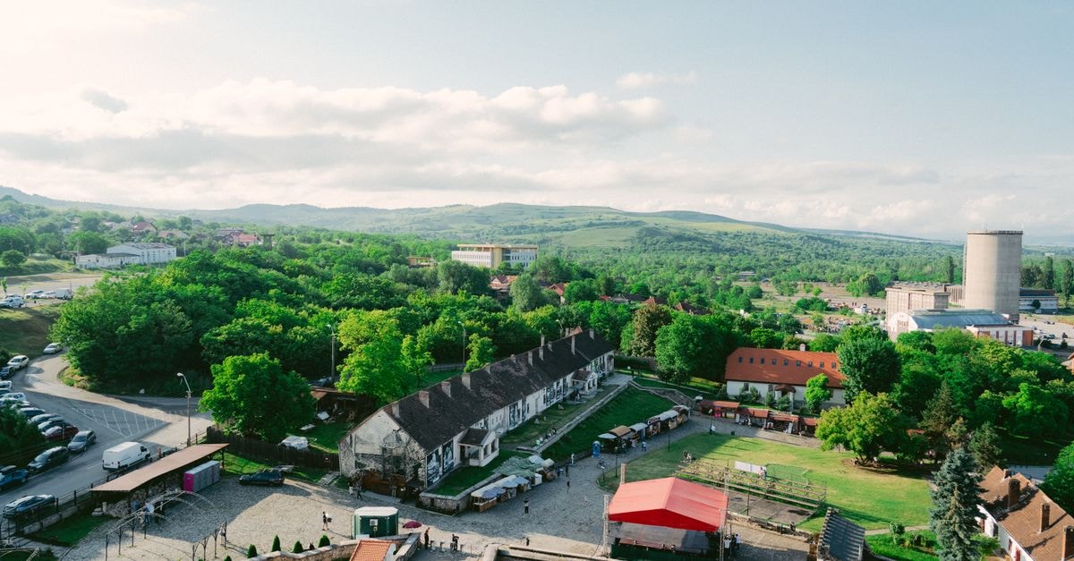Aerial view showcasing a picturesque countryside village with lush greenery under a bright sky.