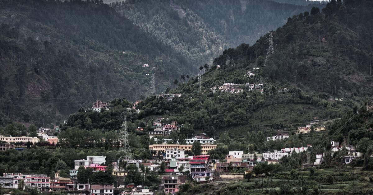 A picturesque view of a hillside town in Jammu surrounded by lush greenery and mountains.