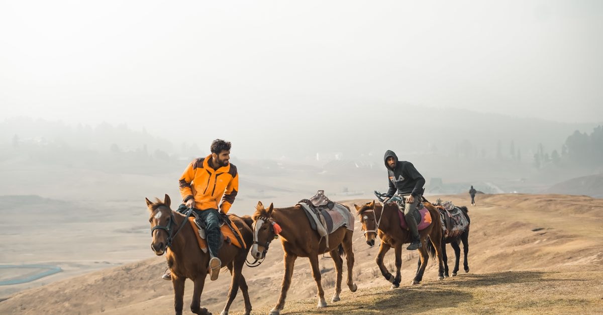 Hafizabad travel guide: riding the chingchi and chasing karahi Men on horseback riding through a misty, hilly landscape.