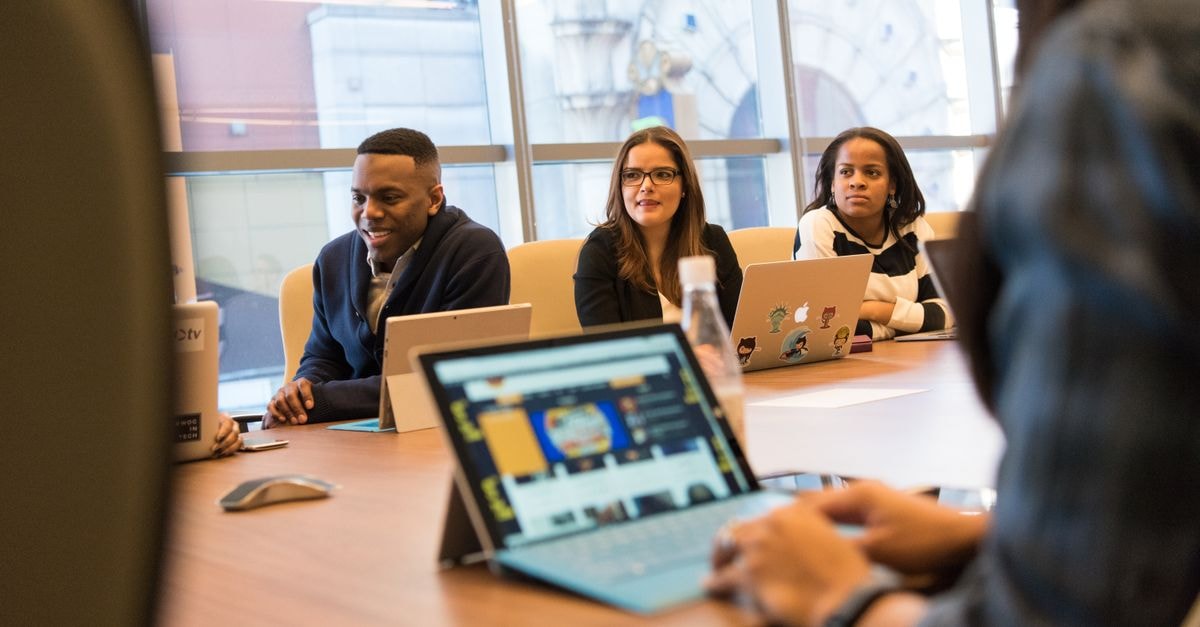 Kelly Services: A Specialty Staffing Business Looking Past a Difficult Quarter A diverse group of professionals working together on laptops in a modern office meeting room.