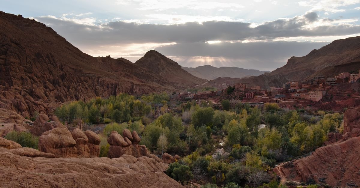 Ouarzazate Travel Guide: A Slow Look at Morocco's Door to the Desert Beautiful valley in Morocco with lush greenery and rocky mountains under a twilight sky.