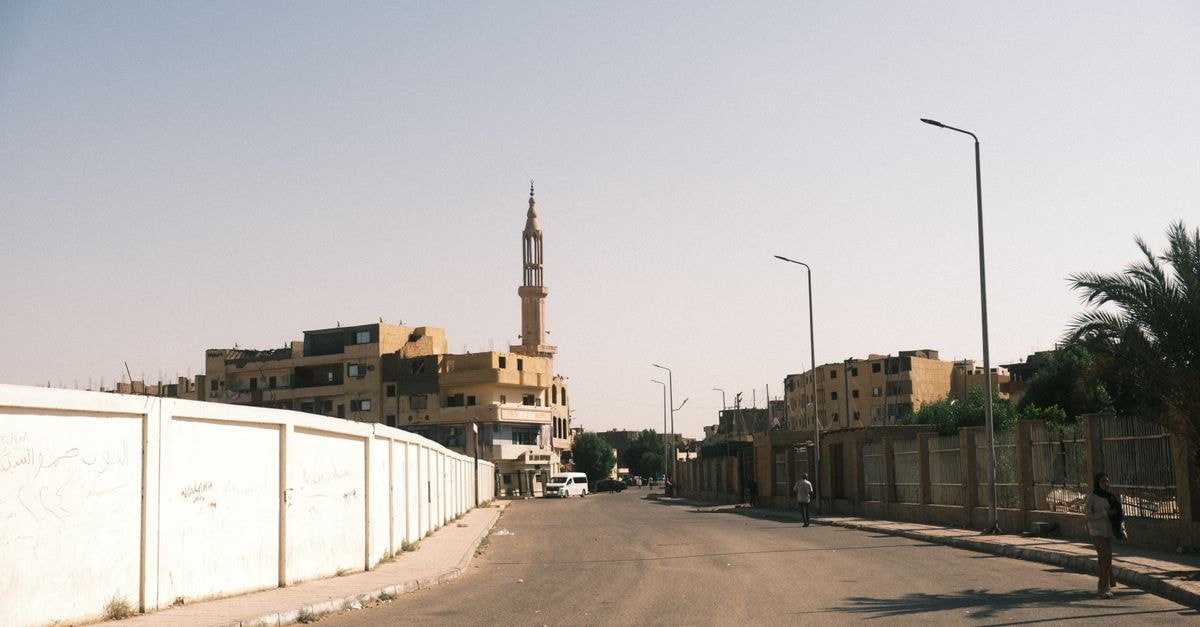 Tranquil street view in Luxor, Egypt featuring a mosque minaret and urban architecture under a clear sky.