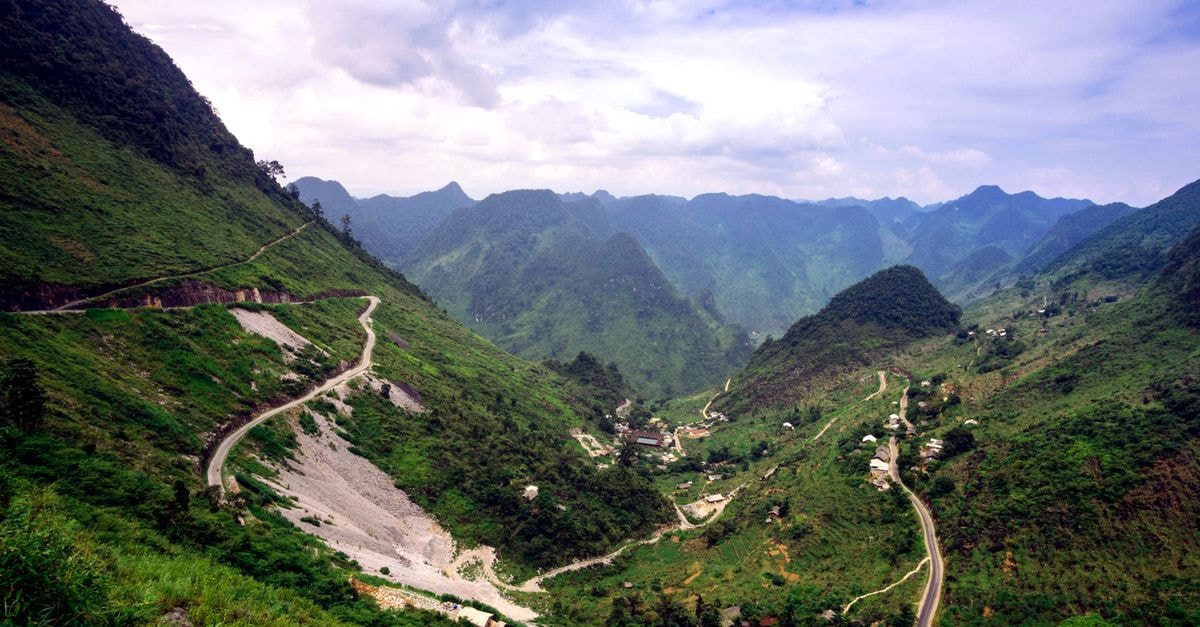 A breathtaking aerial view of winding roads traversing lush green hills and valleys under a clear sky.