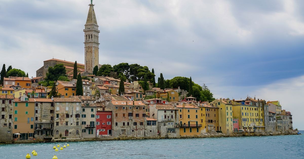 Charming view of Rovinj's colorful waterfront and iconic bell tower on a cloudy day.