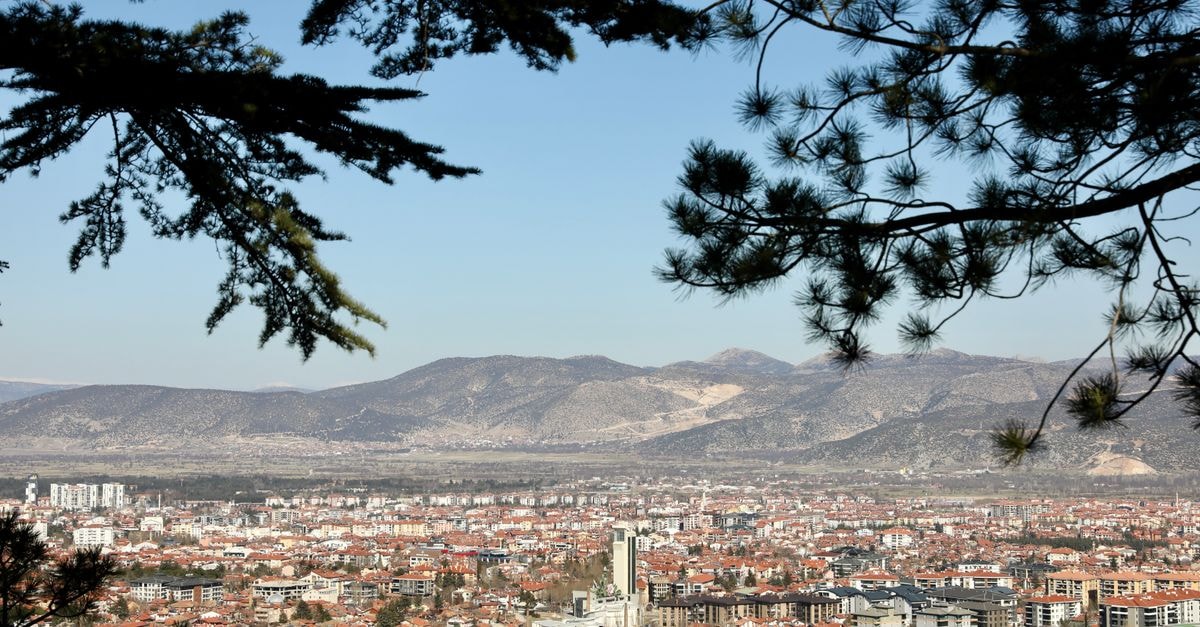 Etnomania in Pristina: A Boutique Stay Steps from Kosovo's Cultural Core A scenic panorama of Isparta city framed by pine trees, showcasing distant mountains under a clear sky.