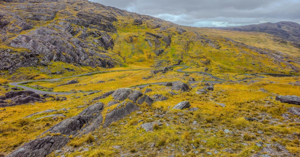 Killarney Plaza Hotel in Killarney: Town Centre Stay with Plaza Suites Breathtaking view of Irish mountain terrain with a winding road under cloudy skies, perfect for travel inspiration.