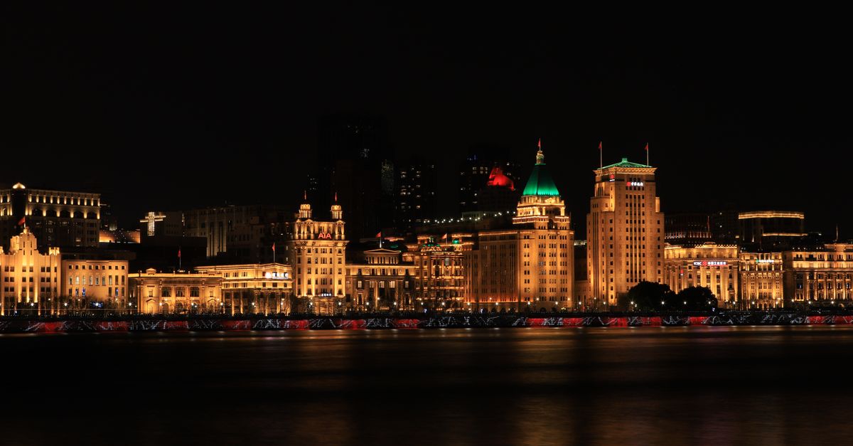 Shanghai Aishengna identified as Chinese firm mass-producing homegrown DUV lithography machines Stunning night view of Shanghai's Bund, showcasing illuminated historic buildings along the waterfront.