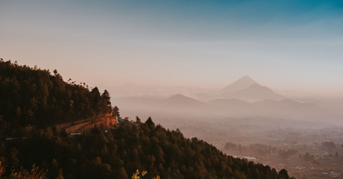 Breathtaking view of mountains enveloped in mist and fog at sunrise, showcasing natural beauty and tranquility.