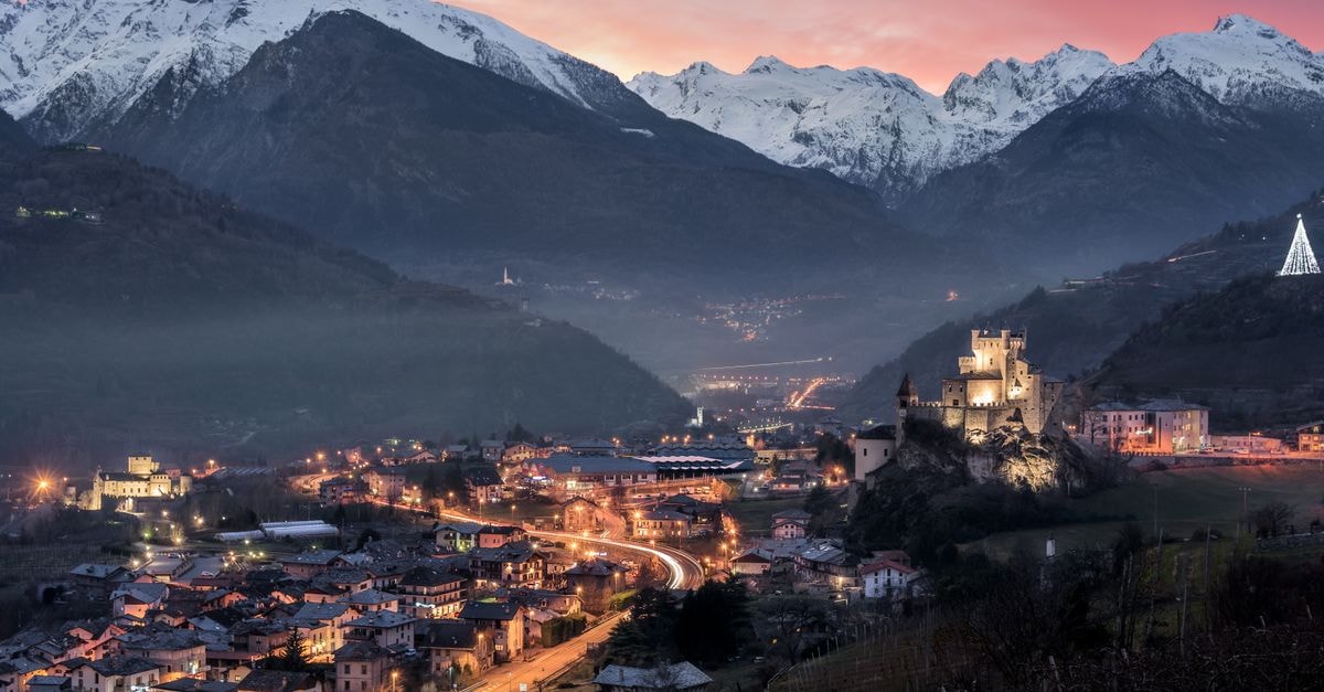 Enchanting evening view of Saint-Pierre with snow-capped mountains and a lit castle.
