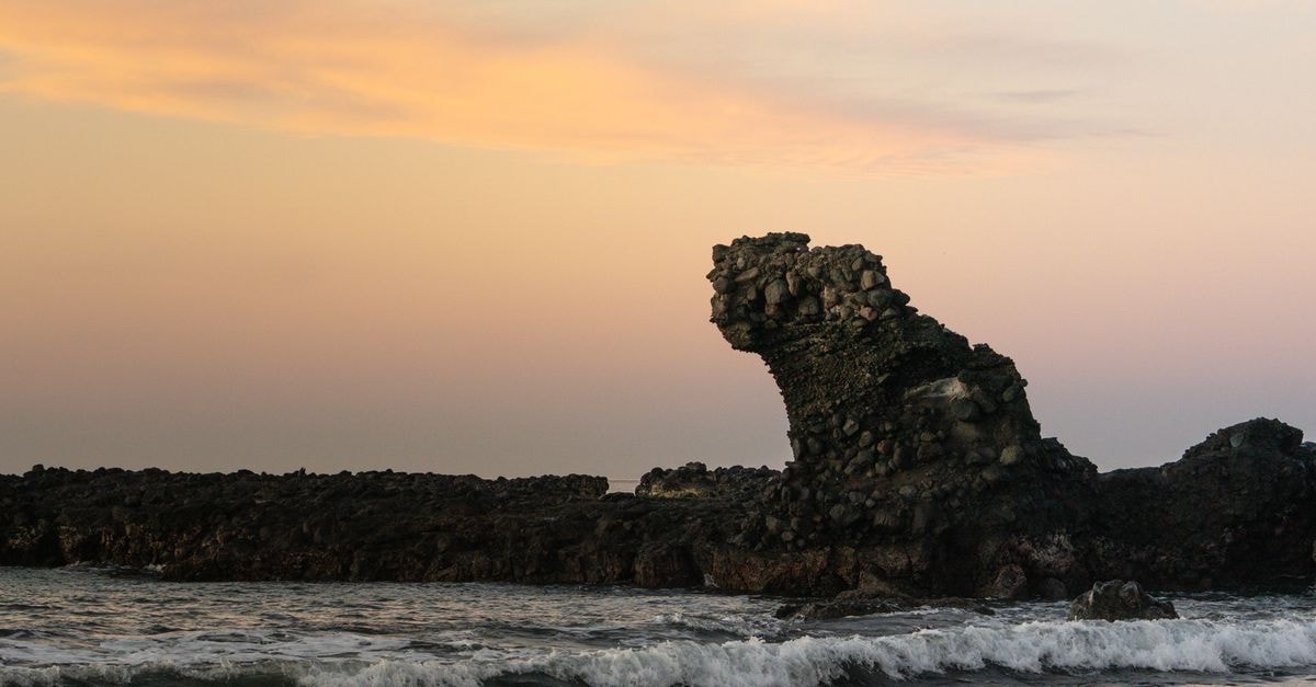 Explore the stunning rock formation at El Tunco beach, bathed in the warm glow of sunset.
