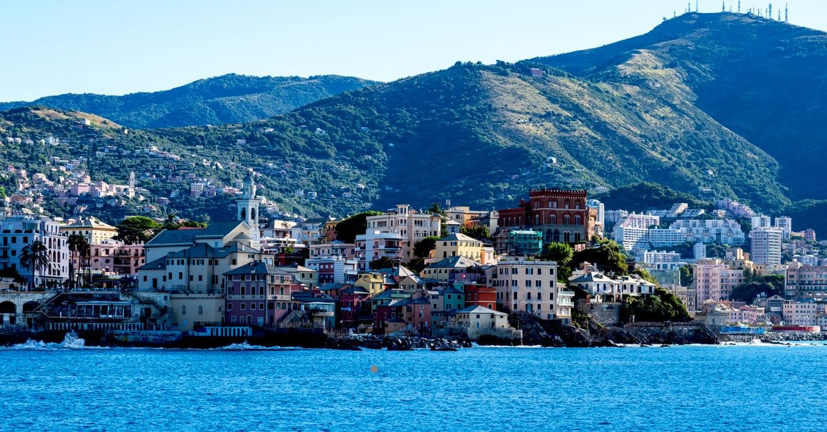 Hotel Ricci in Genoa: Piazza Colombo Steps from the Old Town Beautiful coastal view of Genoa with colorful buildings and scenic hills.