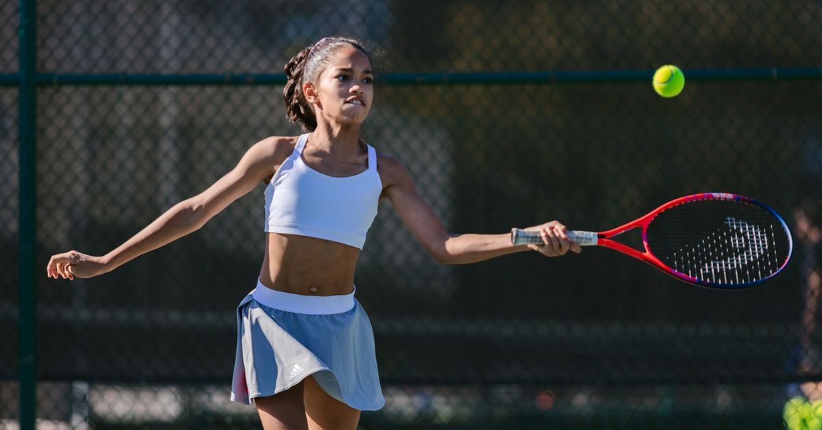 A dynamic young girl practicing her tennis skills on an outdoor court.