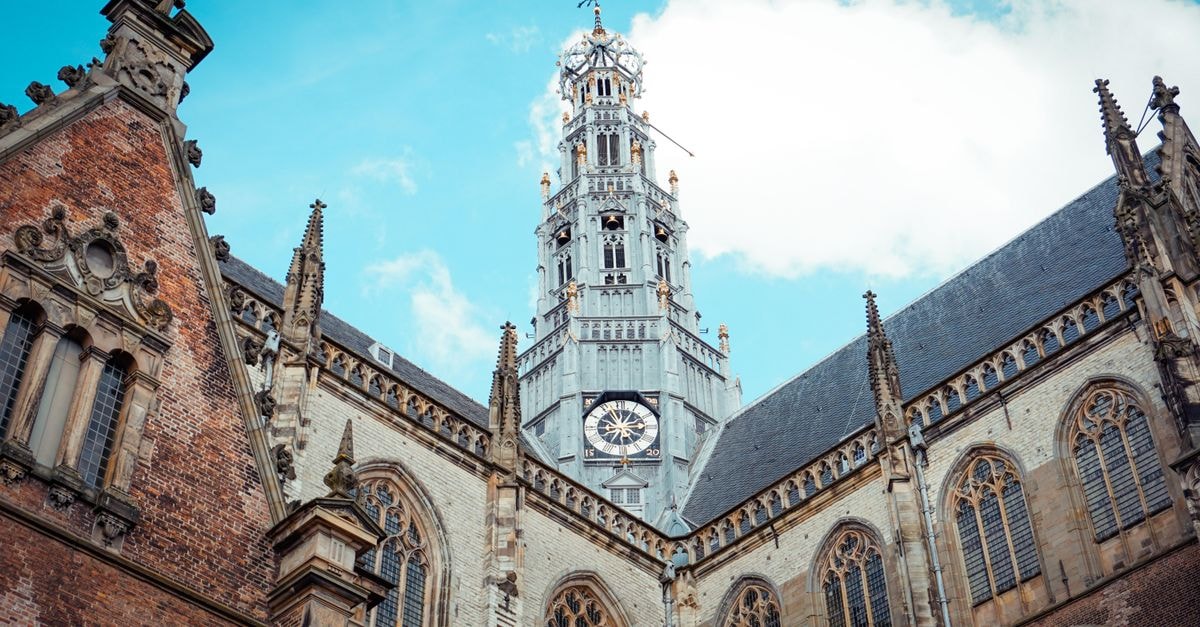 Haarlem Travel Guide: A Gentle Dutch City Worth Slowing Down For Stunning view of a gothic-style church tower under a bright blue sky.