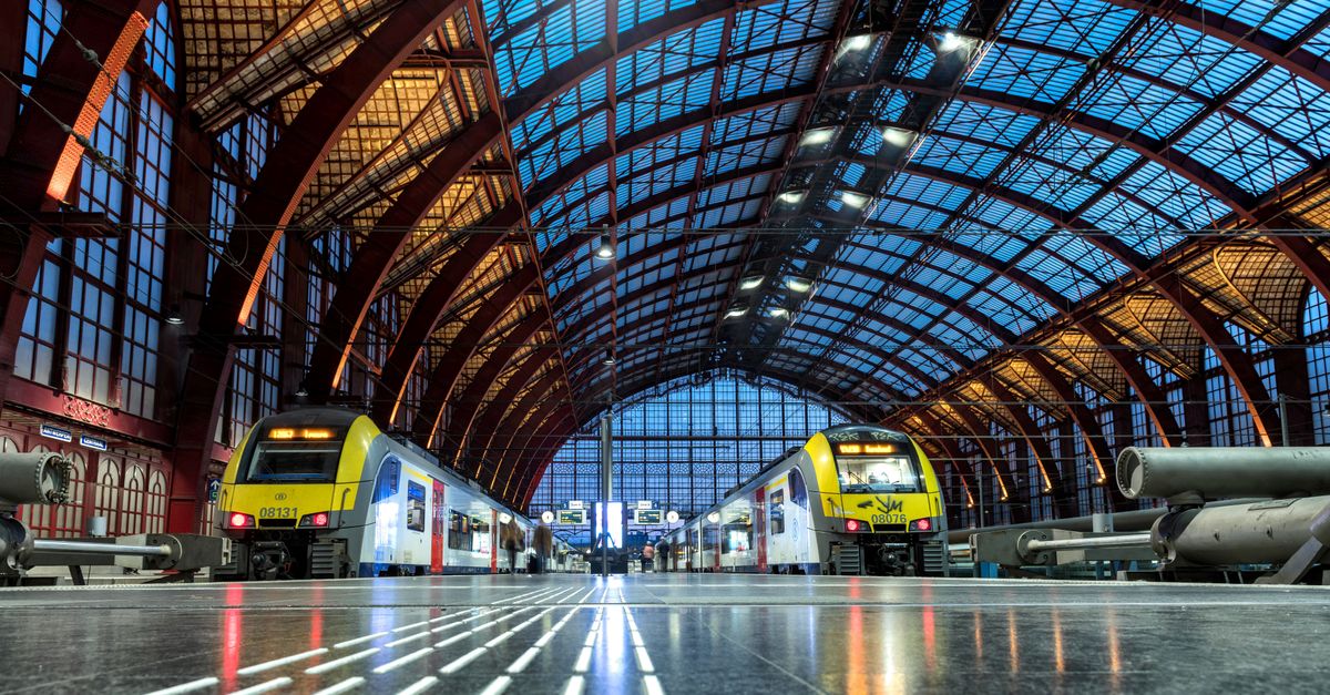 Interior view of Antwerp Central Station showcasing modern trains and stunning architecture.