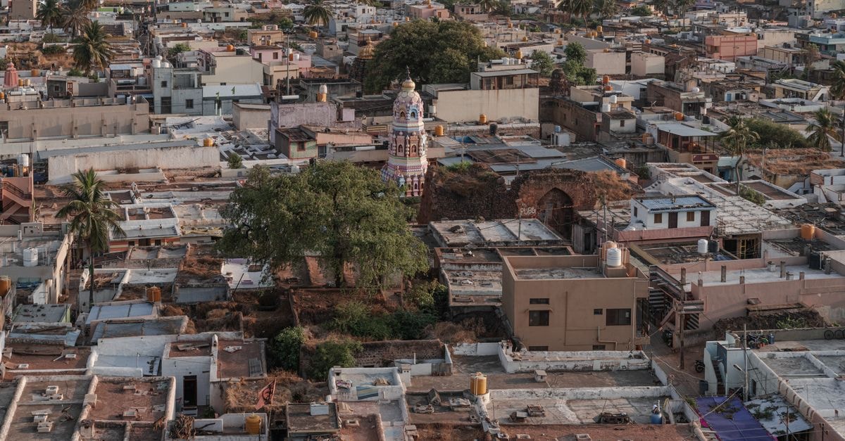 Aerial view of Badami, Karnataka showcasing the town's rooftops and a temple tower amidst lush greenery.