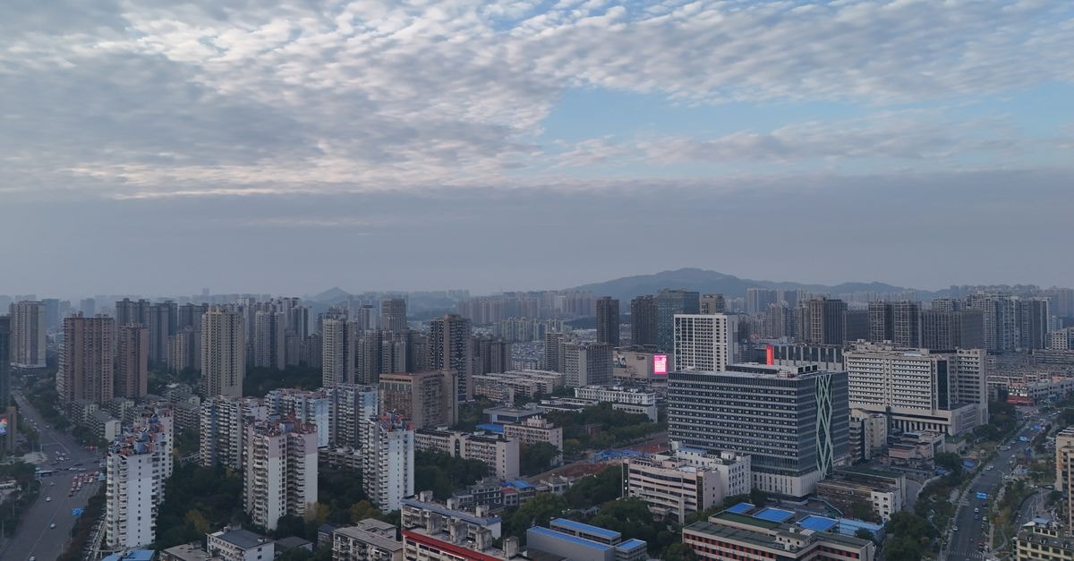 Aerial view of Changsha's skyline showing modern high-rise buildings under a cloudy sky.