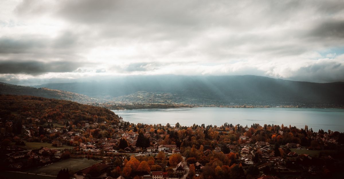 令人屏息的安錫湖空拍秋景，紅葉與壯觀雲層交織。
