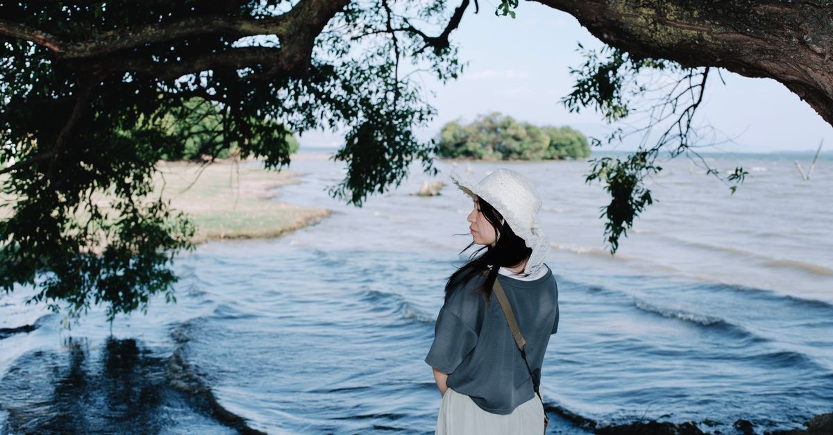 Visiting Vwawa: A Slow-Travel Guide to Songwe's Quiet Corner Woman gazing at lake under tree, providing a serene and contemplative outdoor atmosphere.