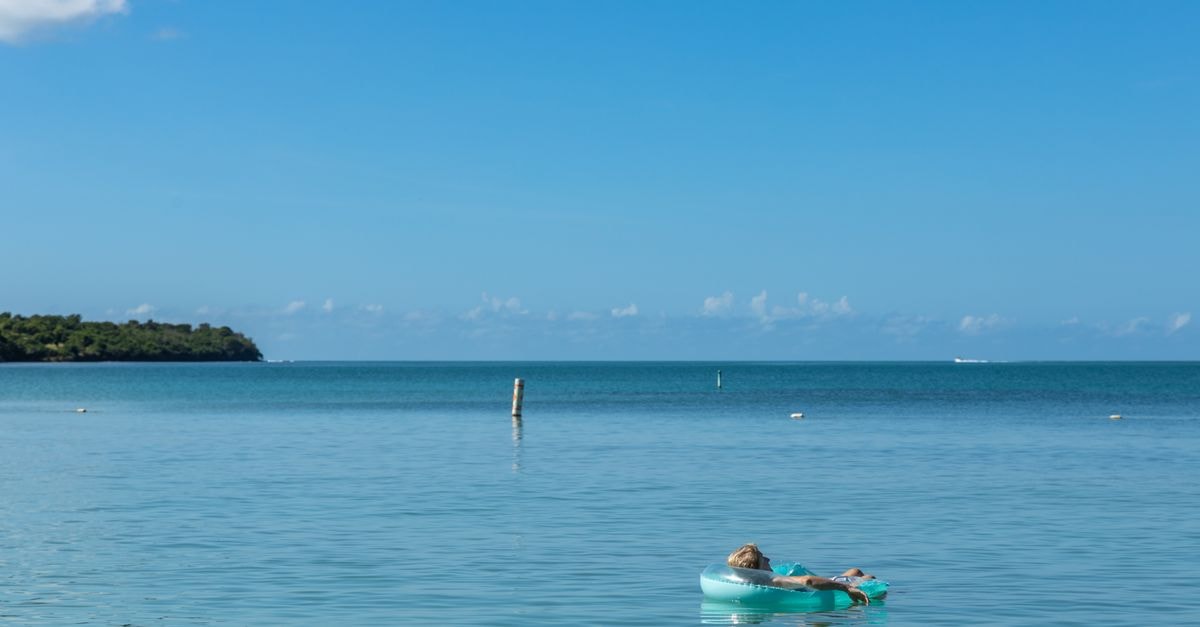 Aquarius Vacation Club in Cabo Rojo: Villas by the Sea Near El Poblado A tranquil scene of a woman relaxing on a float in the beautiful turquoise waters of Cabo Rojo, Puerto Rico.