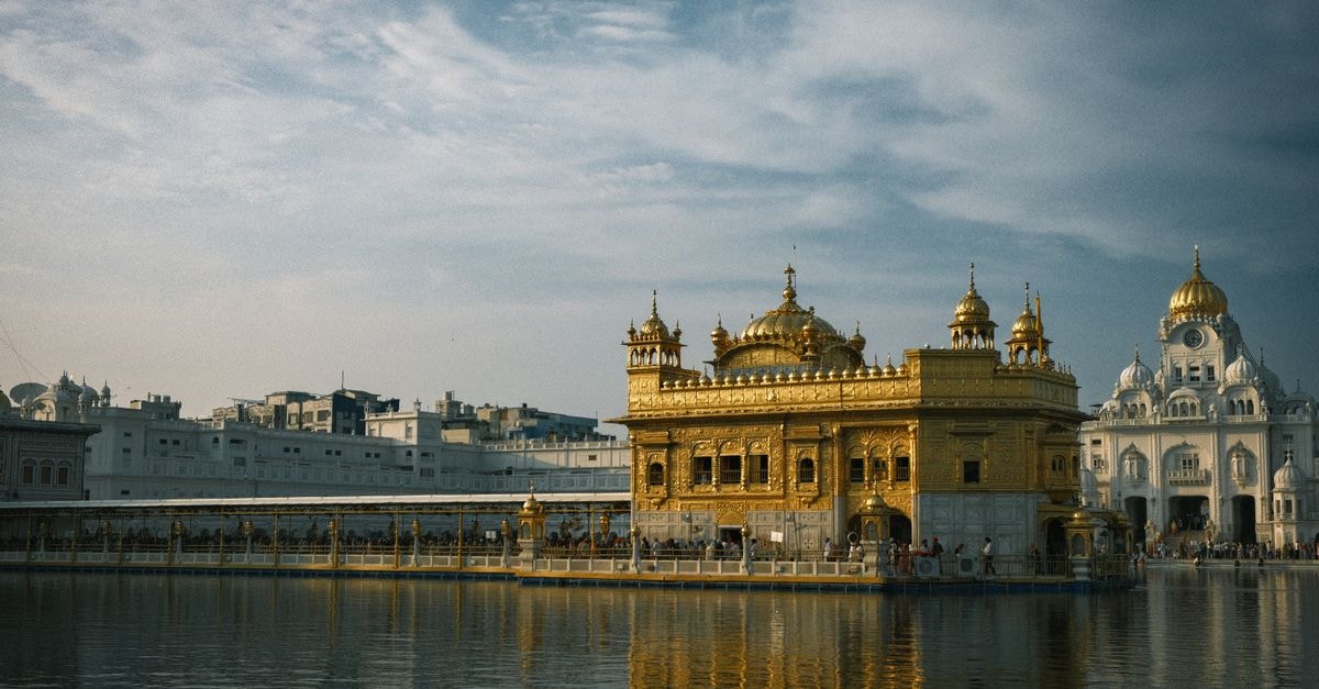 Muridke Travel Guide: Gardens, Heritage, and Punjabi Flavor Stunning view of the Golden Temple in Amritsar at daytime, reflecting in calm waters with a blue sky backdrop.