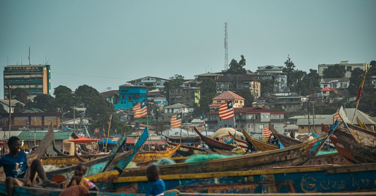 Vibrant scene of fishing boats and urban skyline in Monrovia, Liberia.