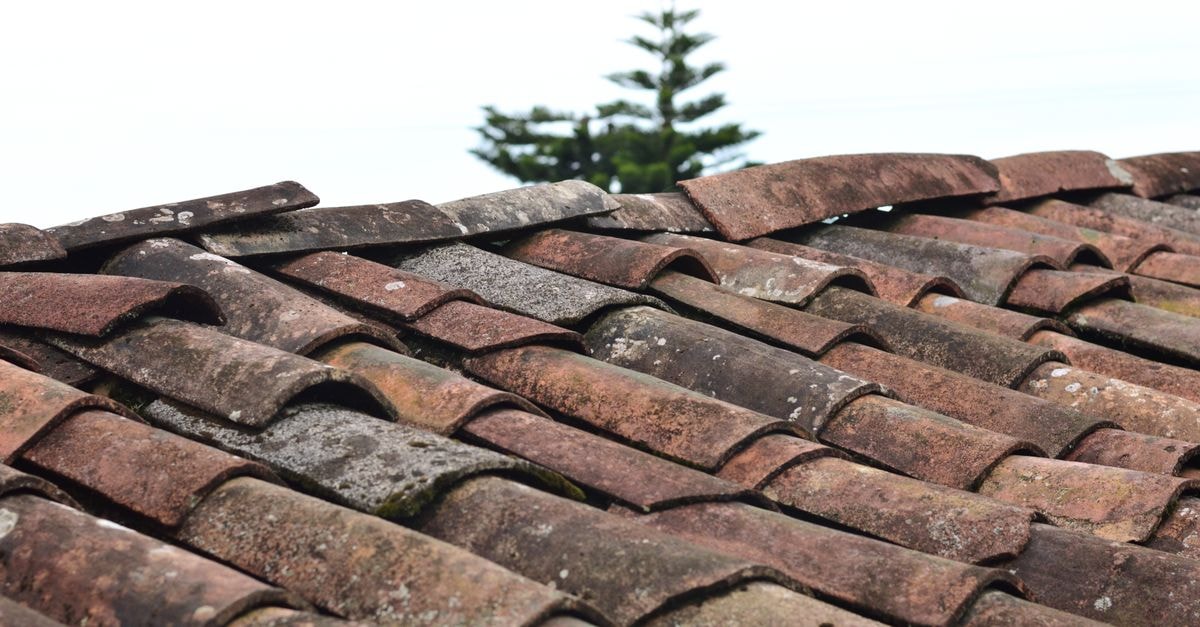 A close-up view of rustic, weathered clay roof shingles under a clear sky in Puebla, Mexico.
