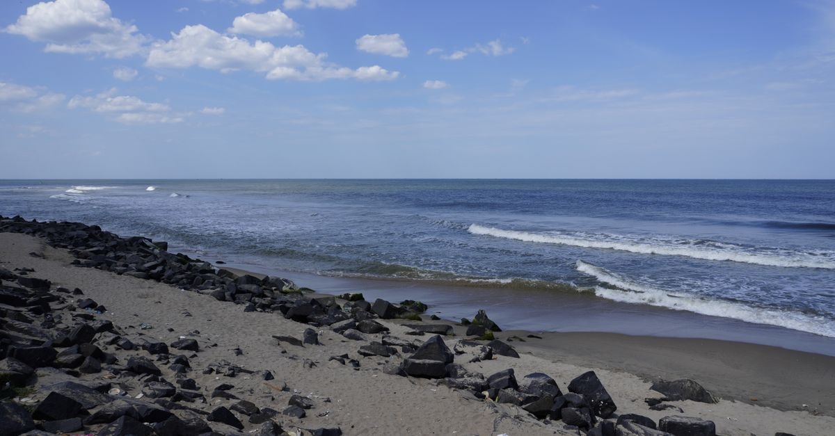Tranquil beach scene with ocean waves and rocky shoreline in Puducherry, India.