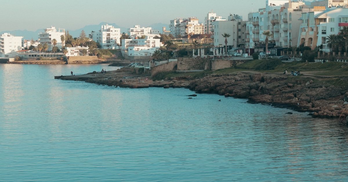 Monastir Travel Guide: Coastal Calm and Local Flavor A serene coastal townscape with urban buildings along the shoreline under a clear sky.