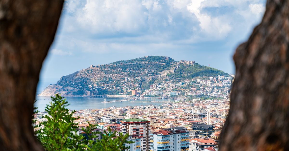A breathtaking aerial view of Alanya, showcasing the cityscape with mountains and the Mediterranean coast.