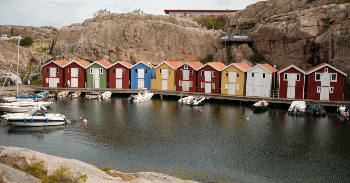 Charming coastal scene of colorful fisherman huts at a Swedish harbor with boats lining the shore.