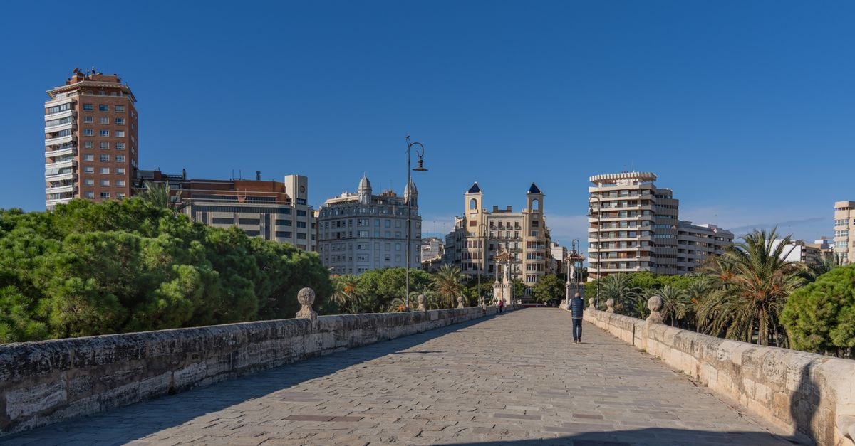 Hotel Vincci Lys in Valencia: Cosmopolitan Stay by the Train Station View of Valencia's skyline from a historic stone bridge on a sunny day, with clear blue skies.