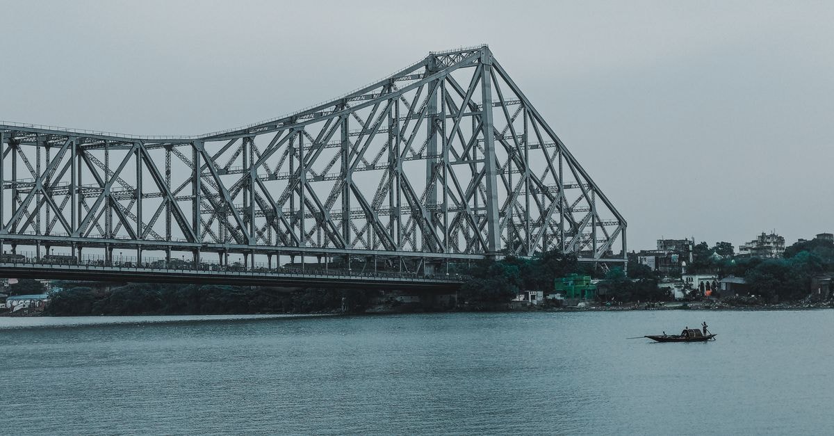 Stunning view of Howrah Bridge spanning the Hooghly River in Kolkata, with a boat floating below.