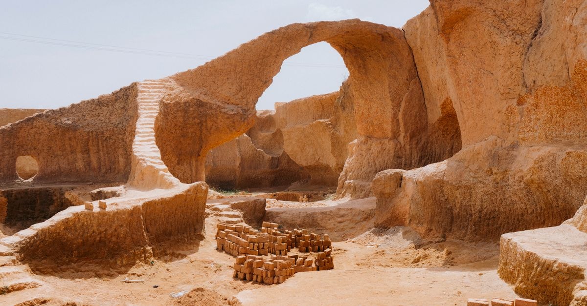 Scenic view of a natural stone archway in a desert quarry with brick formations.