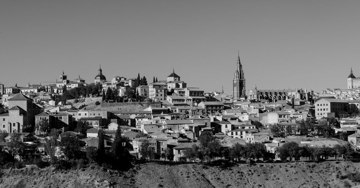 Black and white cityscape of historic Toledo, capturing its iconic landmarks under a clear sky.