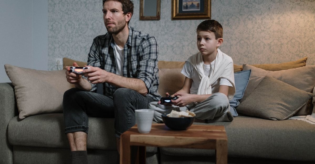 Valve's Steam Frame Sits Nine Days From Its Self-Set Summer Deadline With No Price Or Date A father and son enjoying a bonding moment playing video games together in a cozy living room.