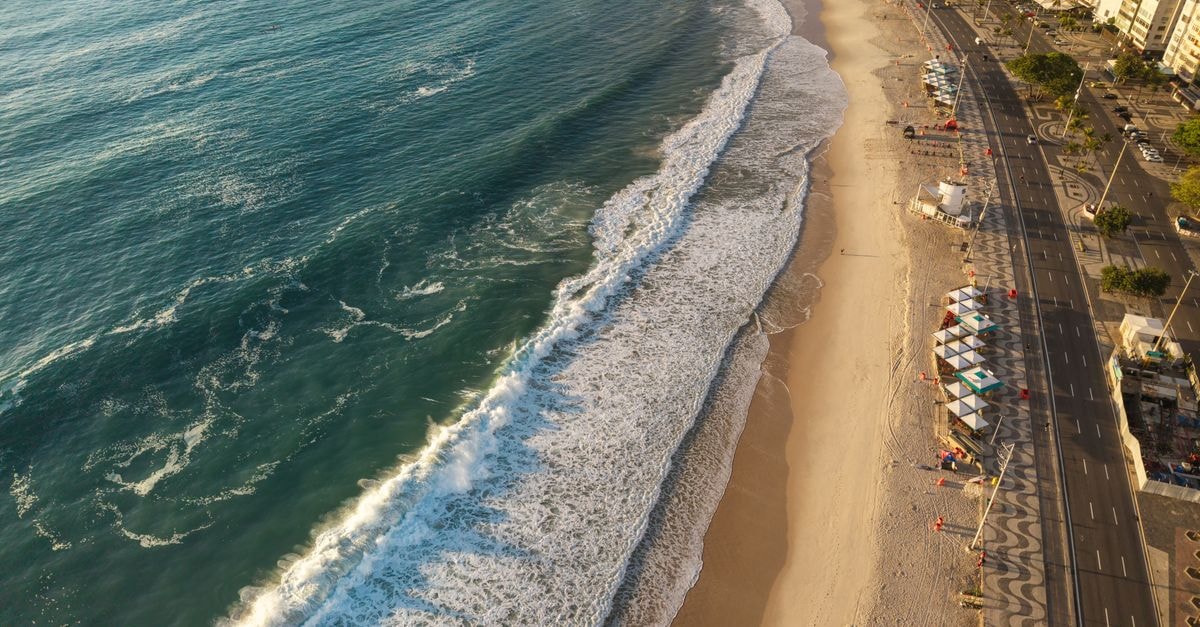 Lauro de Freitas Travel Guide: Beaches, Culture, and Coastal Days Stunning aerial view of Copacabana Beach showcasing golden sunlight and vibrant waves.