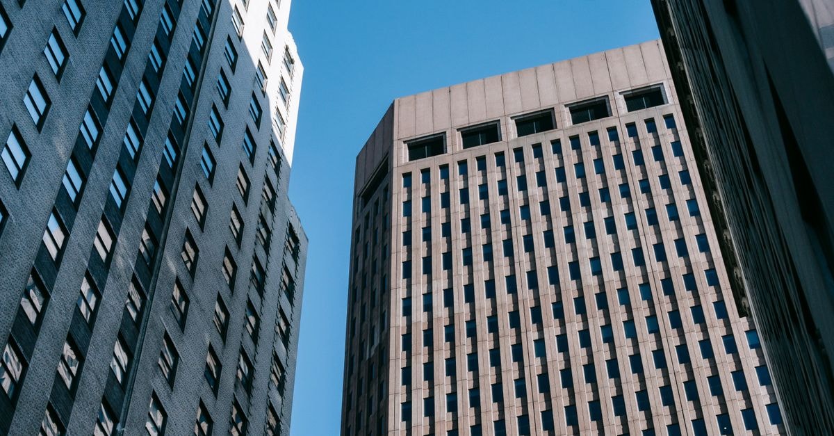 Low angle of multistory commercial and office buildings located in modern district against blue sky