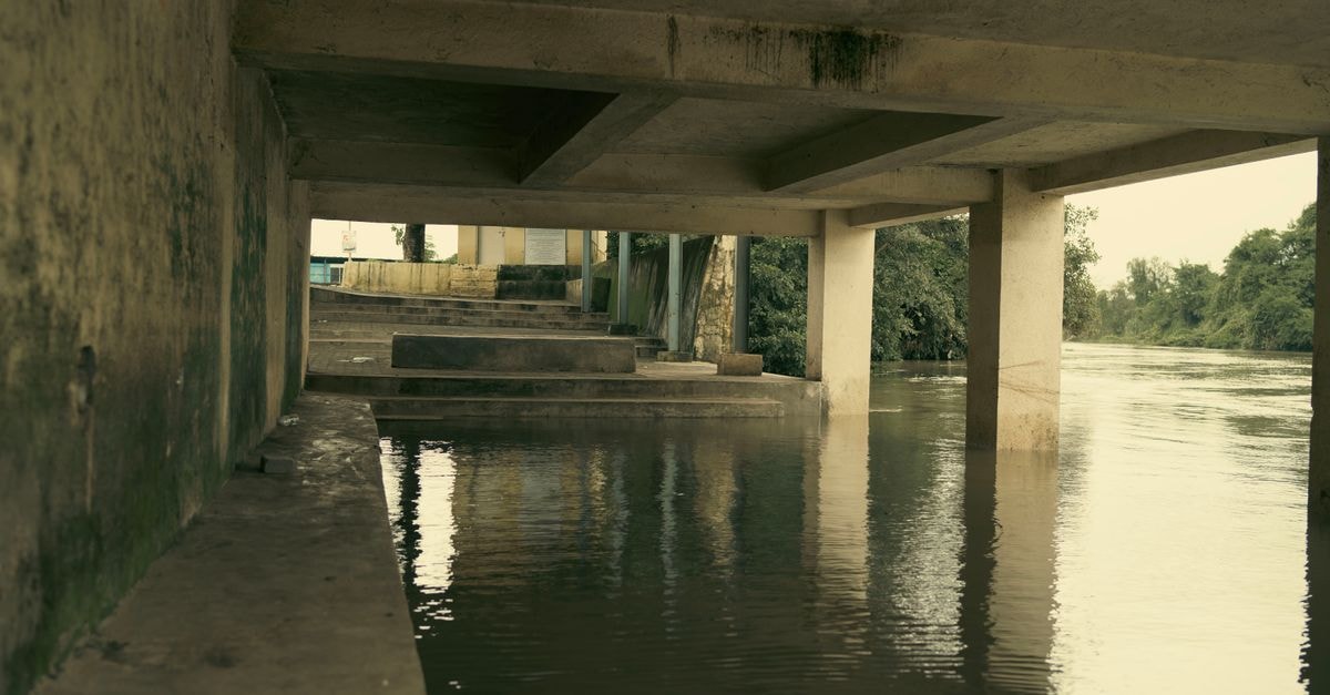 An artistic view of a concrete structure over a calm, flooded river.