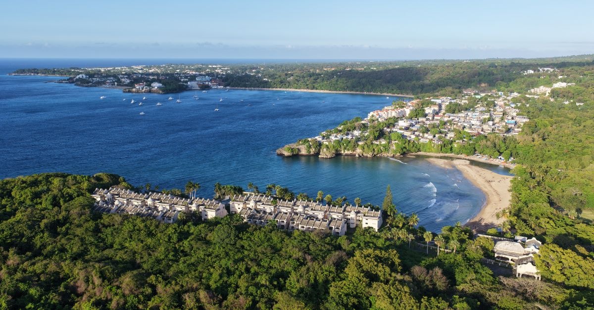 Iberostar Waves Costa Dorada in Puerto Plata: Sea-View Resort with Kayaking and Archery Stunning aerial view of Sosúa Bay, featuring lush greenery and blue ocean in Puerto Plata, Dominican Republic.
