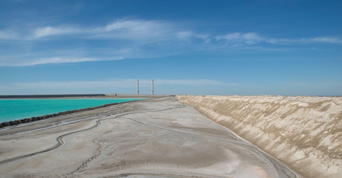 Laayoune travel guide: salt shores and white dunes A stunning coastal landscape featuring turquoise waters and sandy shores under a clear blue sky.