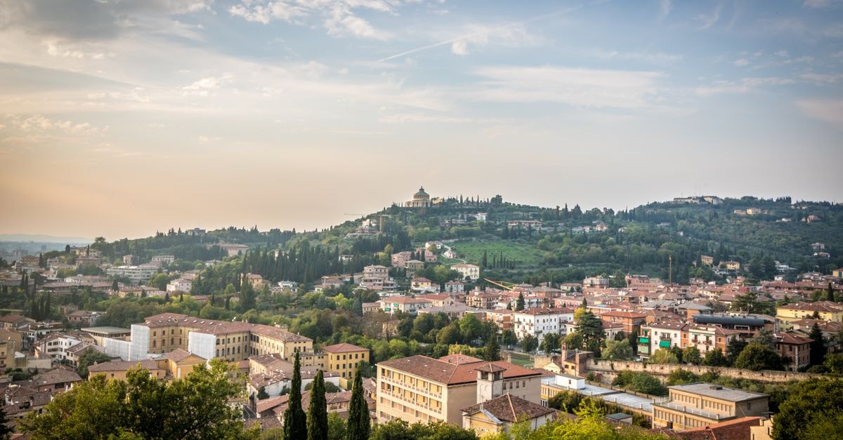 Scenic view of Verona, Italy with hills and buildings under a cloudy sky.
