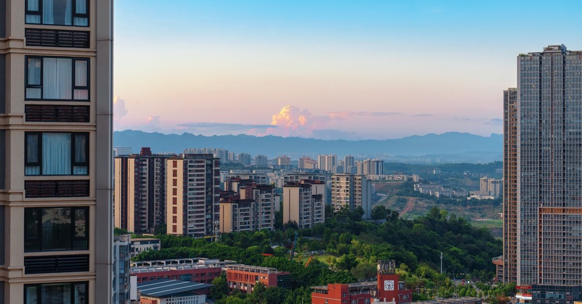 Fuhong International Hotel, Benxi — Refreshed Lobby and Guest Floors A picturesque cityscape featuring modern buildings and distant mountain ranges under a bright sky.