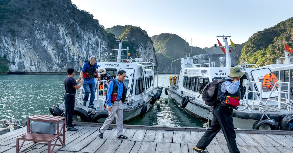 Gorontalo Travel Guide: Quiet Shores of Tomini Bay Tourists disembark boats at a scenic pier surrounded by limestone cliffs.